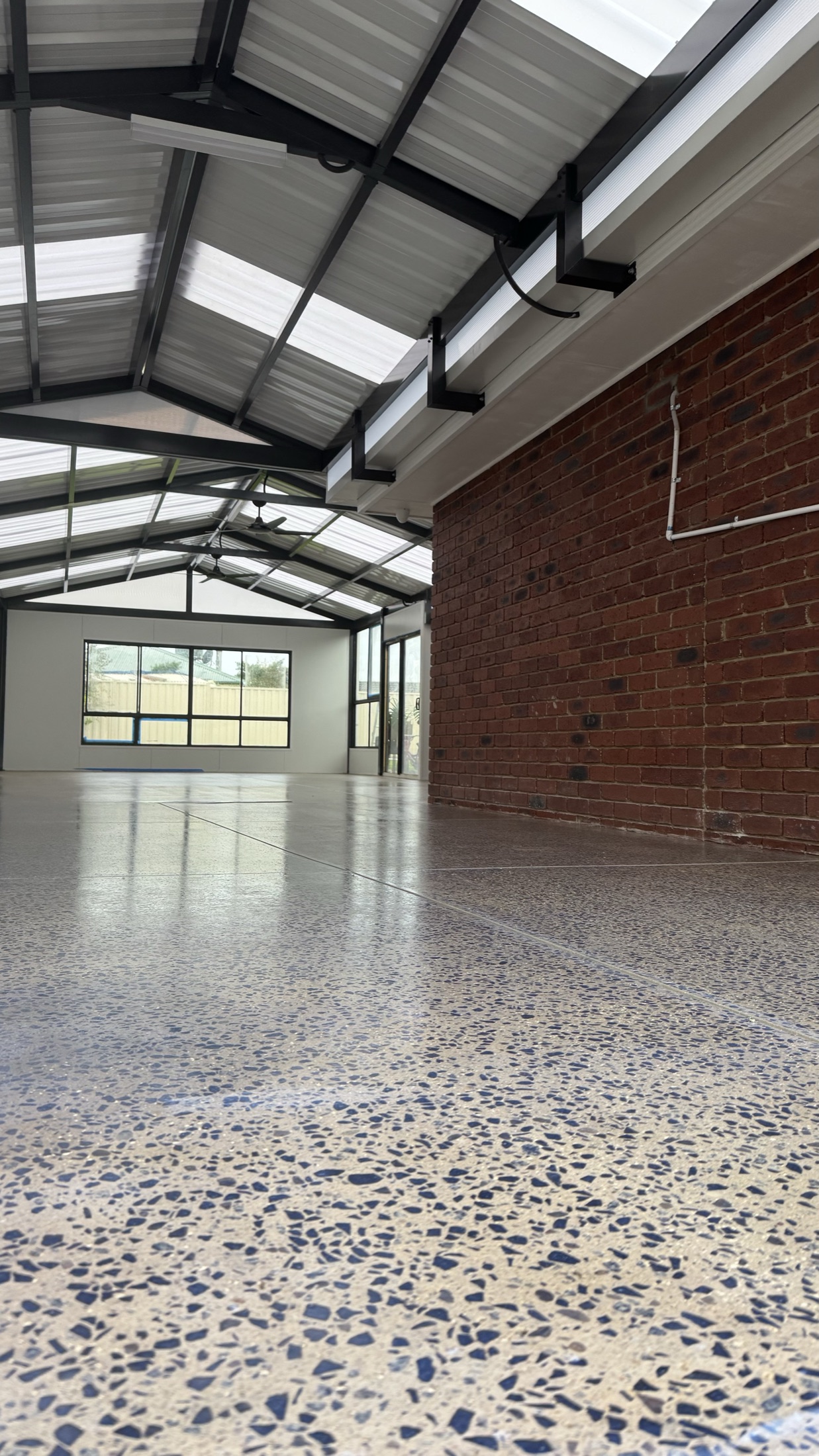 Cream grind and seal floor with blue stone exposure in an alfresco entertaining area, gloss